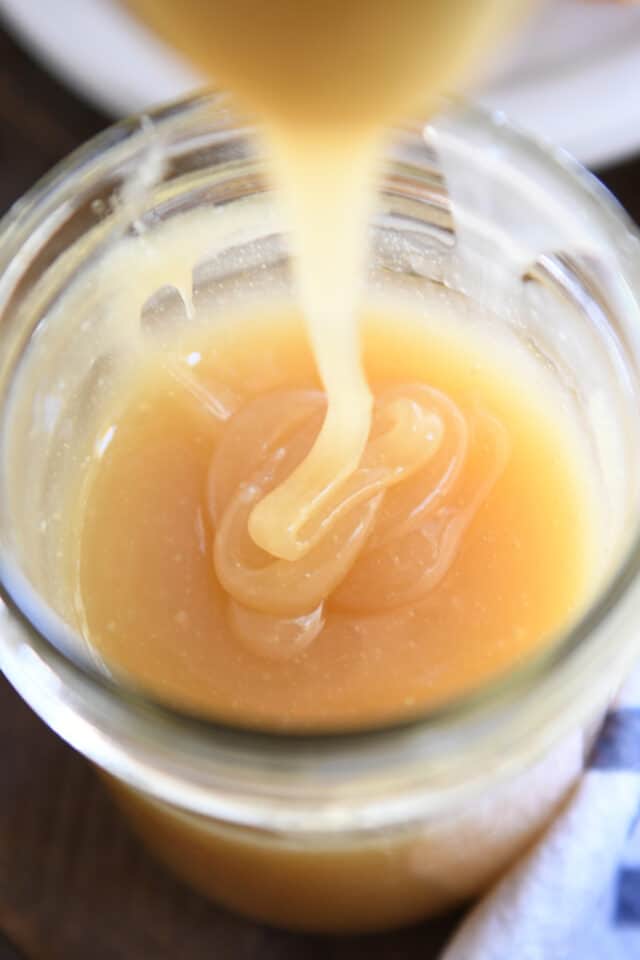 Caramel syrup drizzling into glass jar.
