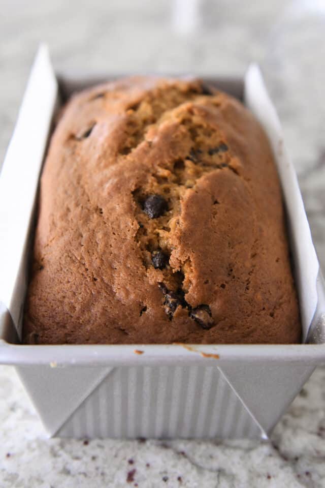 Baked pumpkin bread in silver loaf pan.