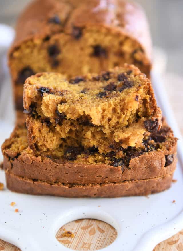 Two slices of pumpkin bread with a third slice on top broken in half.