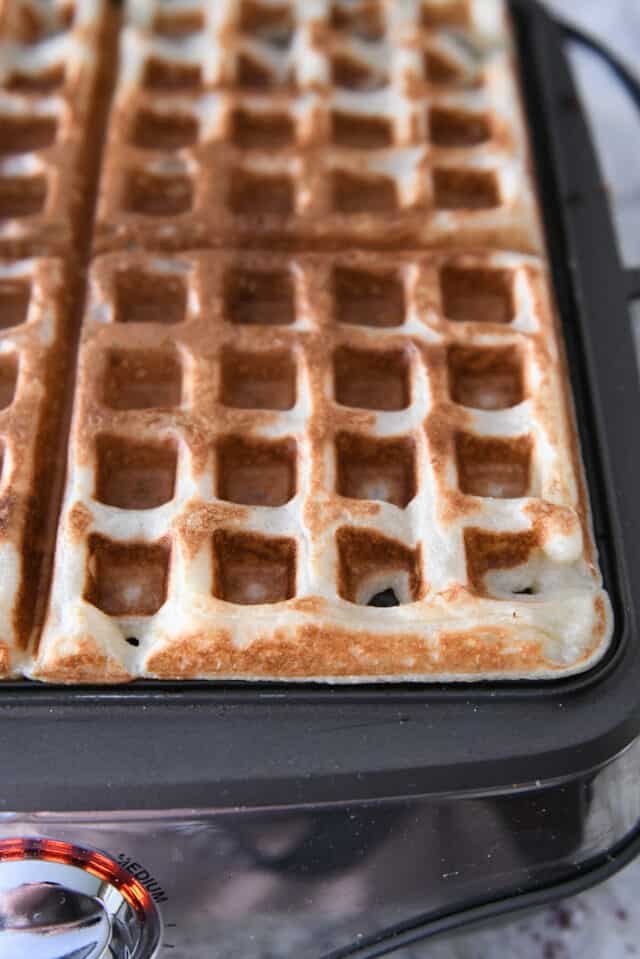 Open waffle iron with cooked waffle.