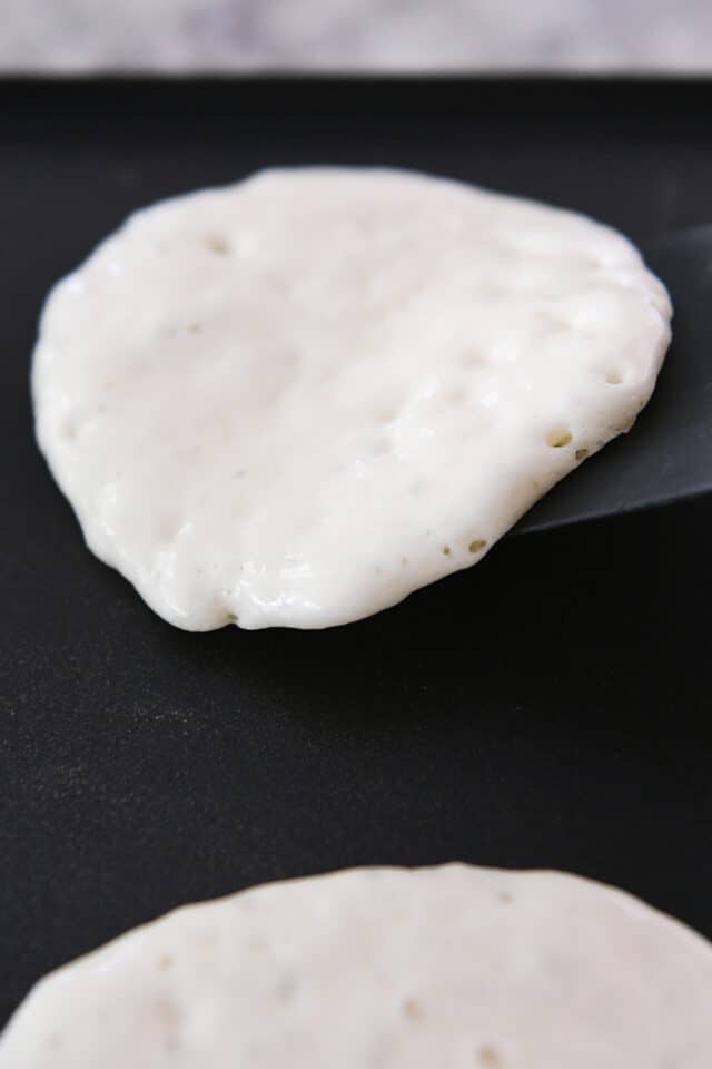 Flipping pancake on griddle with spatula.