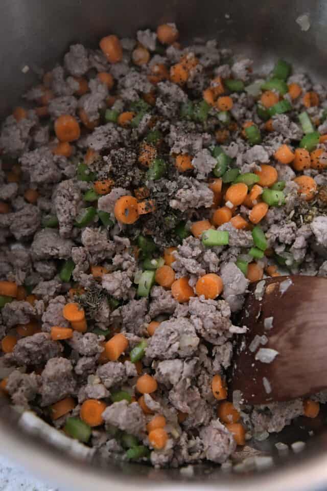 Cooking ground sausage, carrots, celery and seasonings in pot.