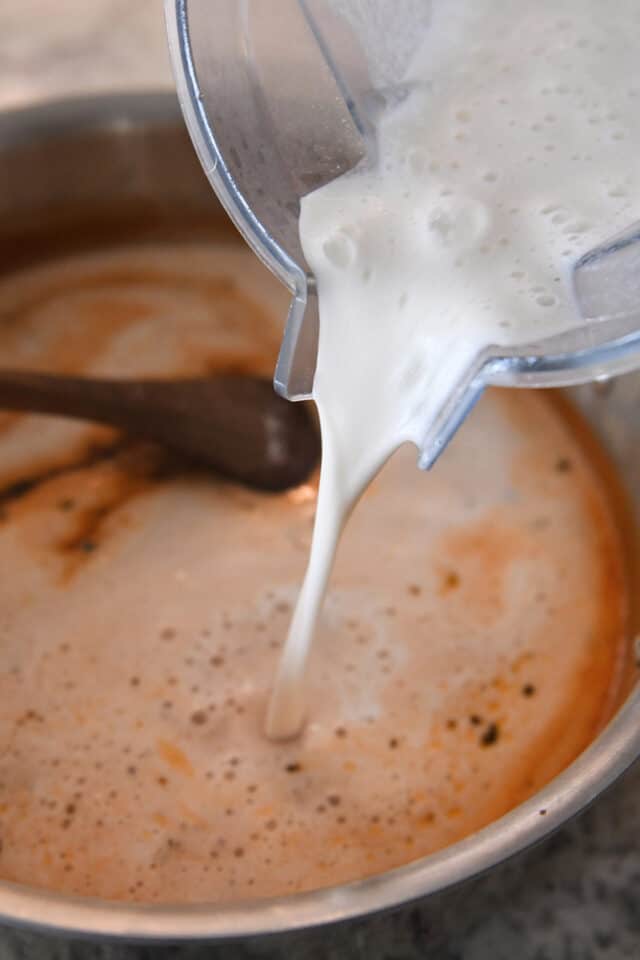 شیر و دوغاب آرد را در قابلمه با آب گوجه فرنگی می ریزیم.