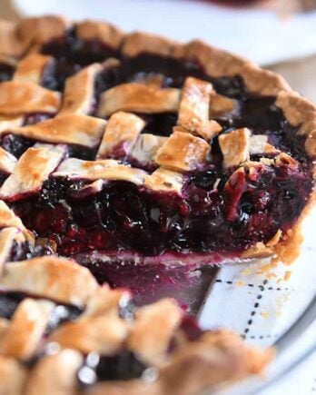 Triple berry pie in glass pie dish with one piece removed.