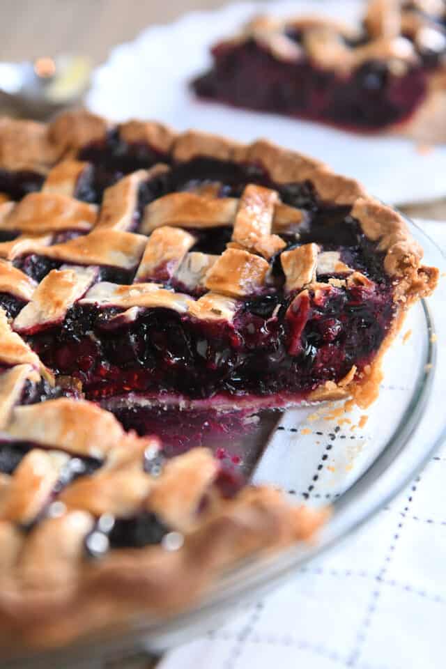 Piece removed from triple berry pie in glass pie plate.