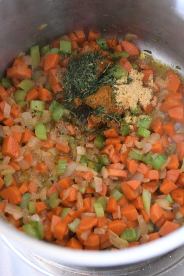 Sauteeing carrots, onions, celery, curry powder, and parsley in pot.