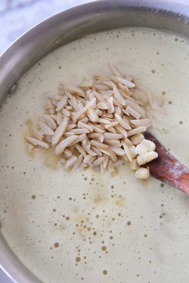 Slivered almonds in pot with wooden spoon and broth.