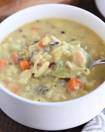 White bowl with spoon scooping up chicken and wild rice soup.