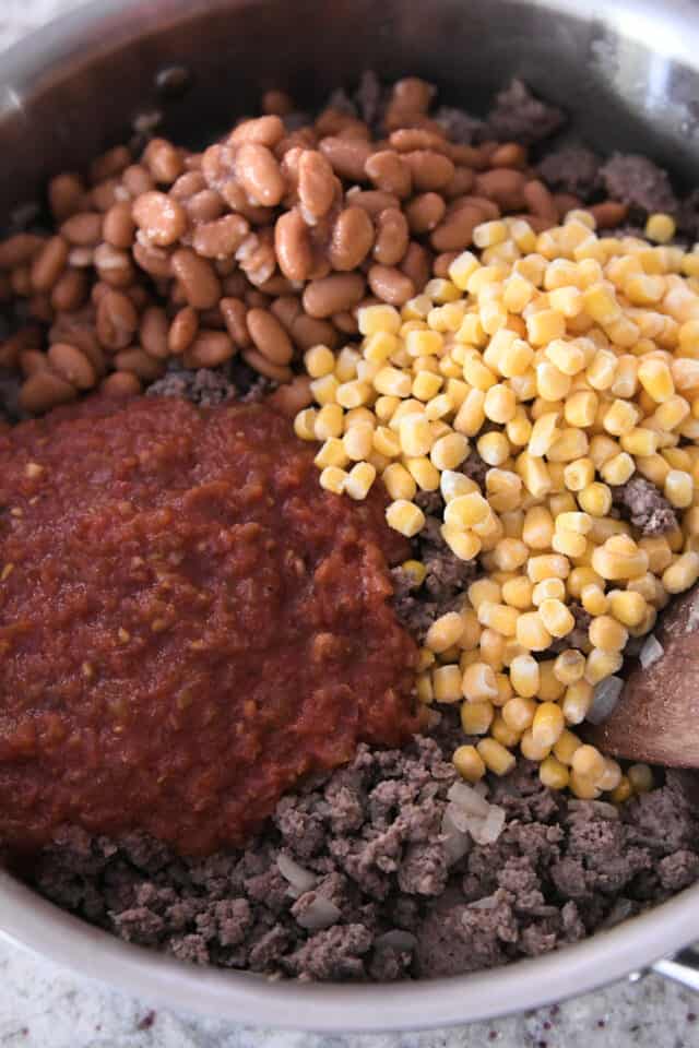 Salsa, pinto beans, corn and beef in stainless steel pan.