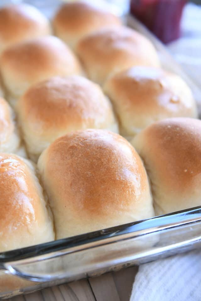 Baked and buttered soft dinner rolls in glass pan.
