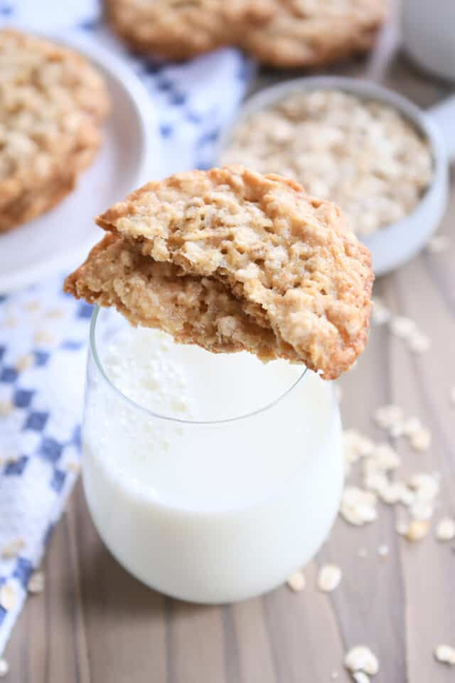 Two cookie halves sitting on top of glass of milk.