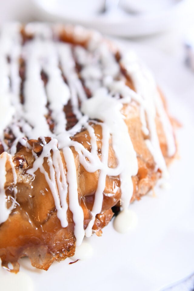 Side view of upside down apple pie with glaze drizzled over the top.