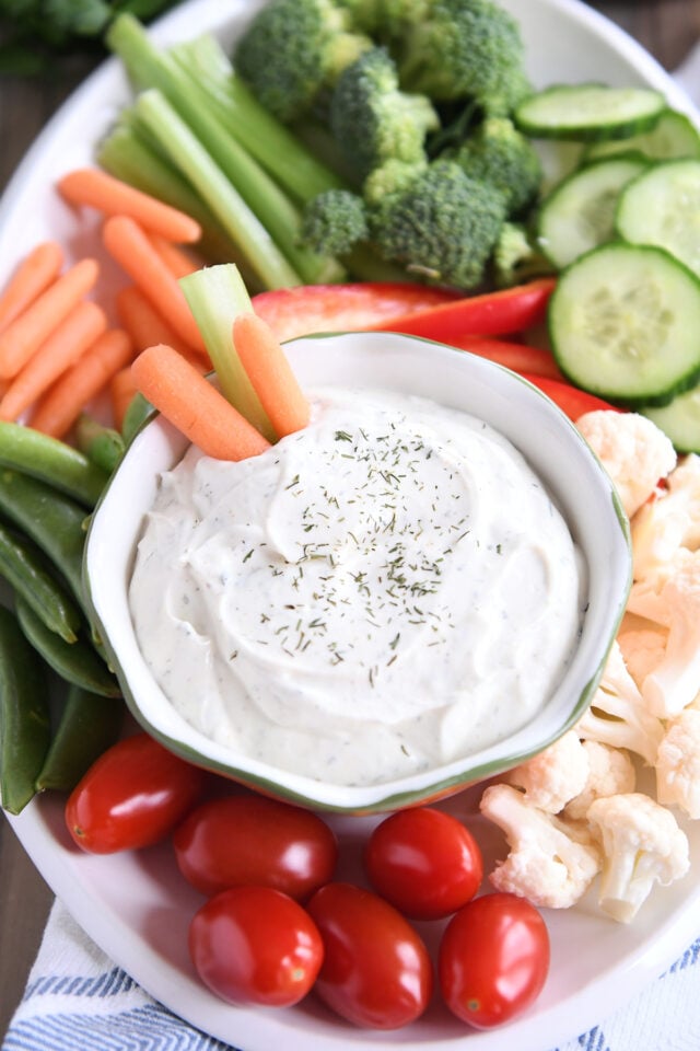 Two carrot sticks and a stick of celery in a bowl of vegetable dip.