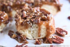 Caramel pecan sticky bun with pecans on edges on parchment paper.