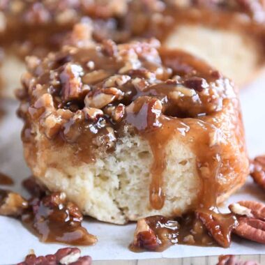 Caramel Pecan Sticky Bun with pecans on the sides on parchment paper.