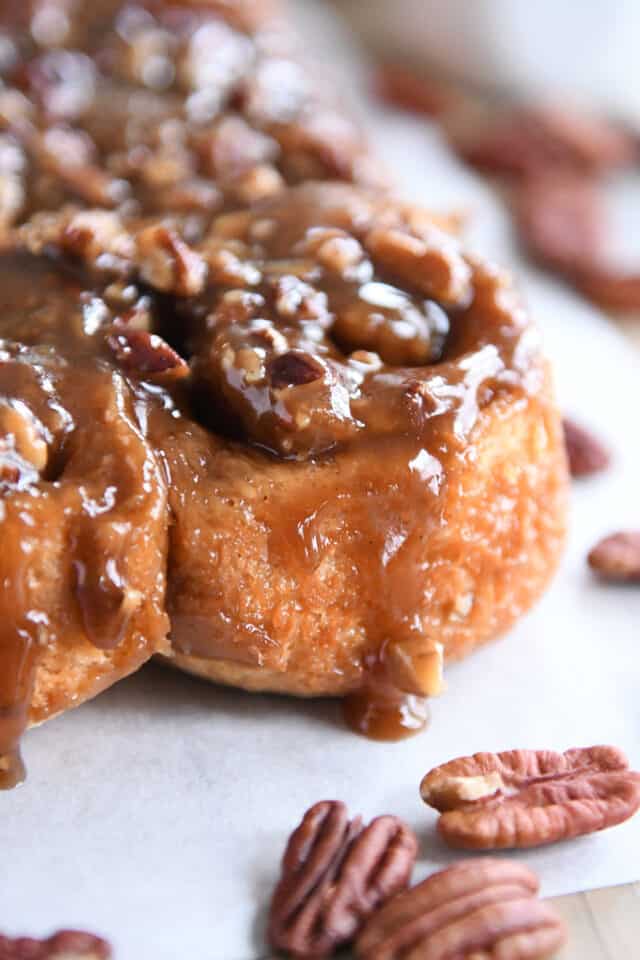 Caramel dripping down the side of sticky buns with pecans.