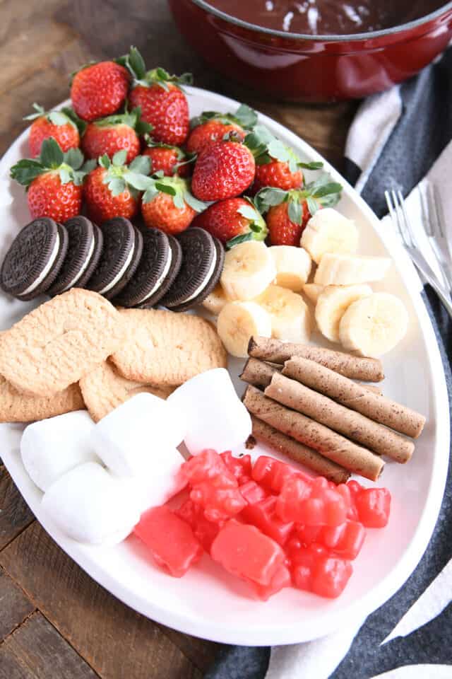 Oreos, strawberries, bananas, marshmallows, pirouette cookies on white tray.