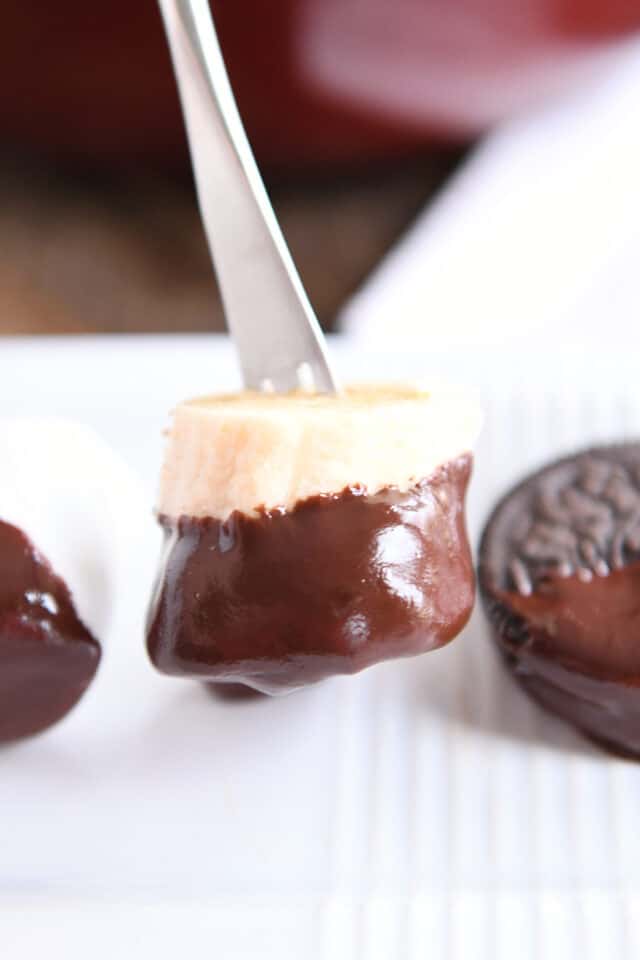 Banana dipped in chocolate on white tray.