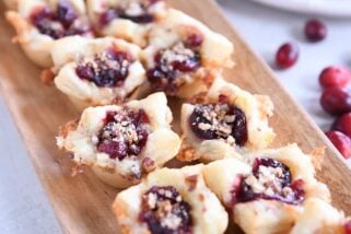 Six cranberry brie bites on wood platter.