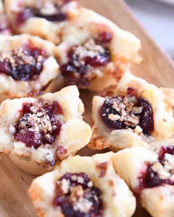 Six cranberry brie bites on wood platter.