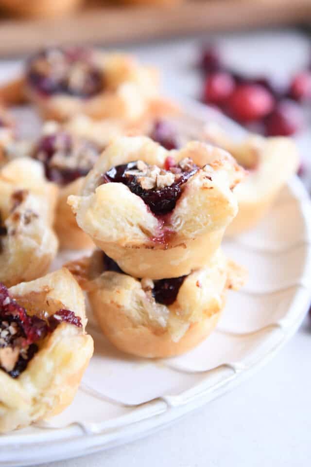 Two cranberry brie bites stacked on top of each other on white plate.