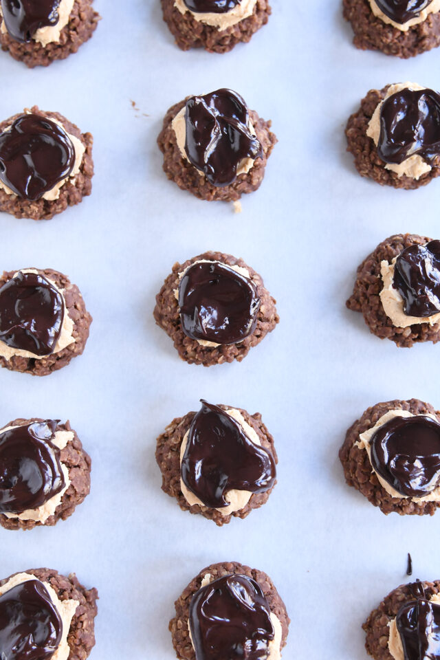 Lots of no-bake chocolate peanut butter horse cookies on white parchment paper.