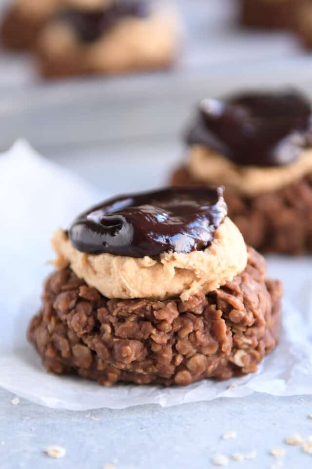 No bake cookie with peanut butter frosting and chocolate ganache on square of parchment paper.