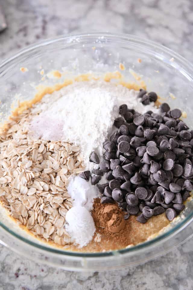 Glass bowl with oatmeal, flour, chocolate chips, cinnamon, salt, banana dough.