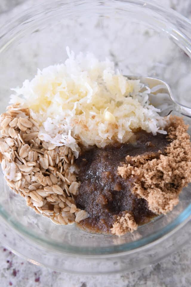 Glass bowl with oats, coconut, brown sugar and butter.