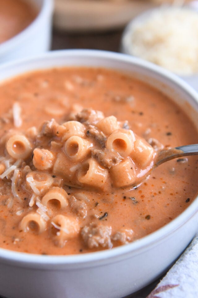 Spoon with noodles, ground beef, tomato broth.