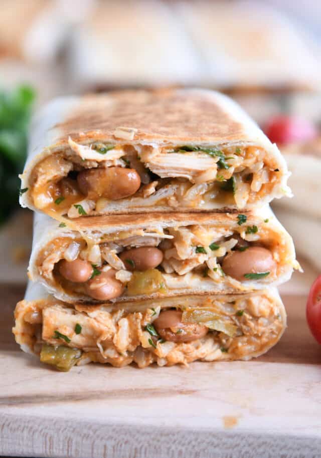 Three tortilla wraps stacked on a wood board.