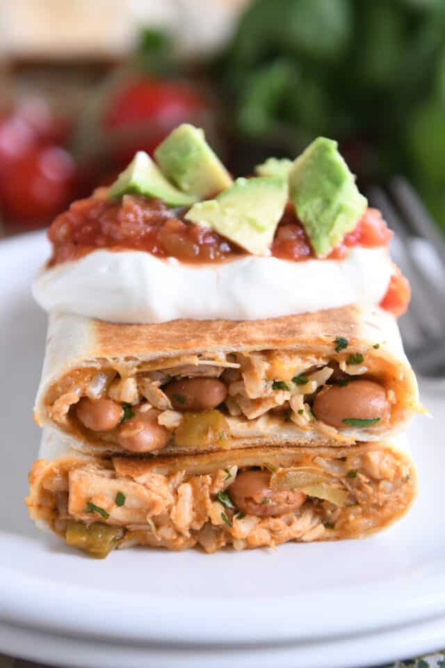Two halves of crispy wraps stacked with sour cream, salsa and avocado.