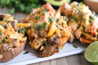 Several sweet potatoes on white tray with mushrooms, bell peppers, and cheese.