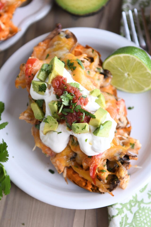 Top down view of sweet potato loaded with chicken, veggies, sour cream, salsa, and avocado.