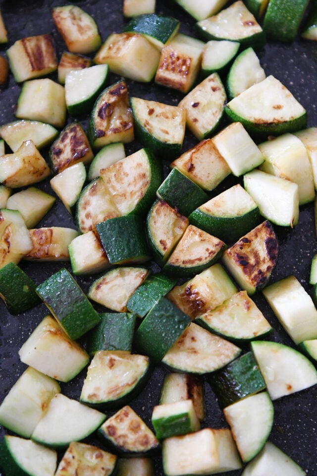 Golden cooked zucchini pieces in skillet.