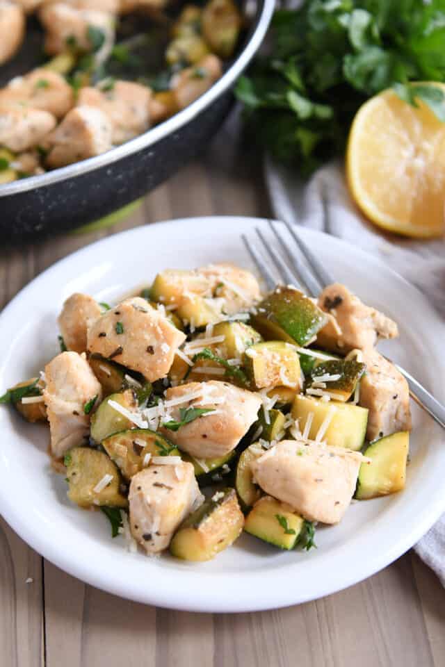Chicken, zucchini and parmesan cheese on white plate.