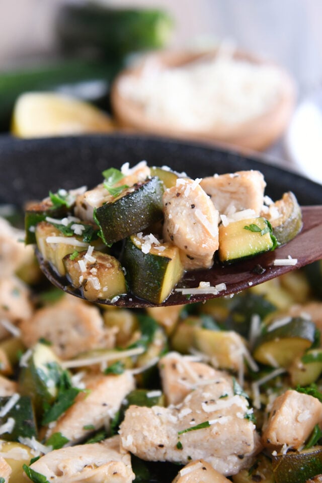 Wooden spoon with zucchini, chicken and parmesan cheese.