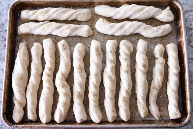 Breadsticks rising on sheet pan.