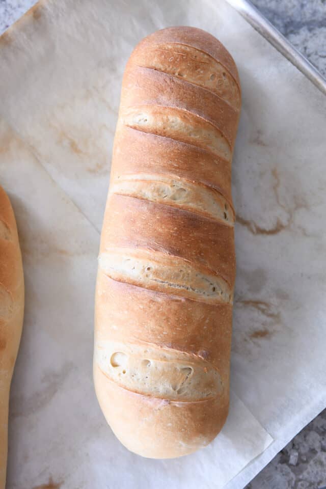 Baked loaf of homemade French bread on parchment paper.