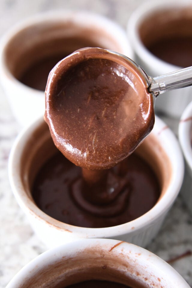 Scooping chocolate cake batter into ramekin.