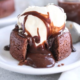 Molten lava cake on white plate with ice cream and spoon.