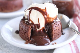 Molten lava cake on white plate with ice cream and spoon.