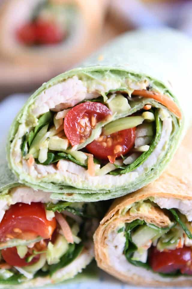 Half of a turkey avocado veggie wrap stacked on top of two other wraps.