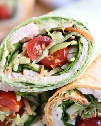 Turkey wrap in spinach tortilla stacked on two other wraps.