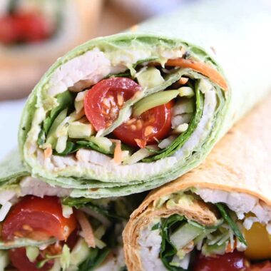 Turkey wrap in spinach tortilla stacked on two other wraps.