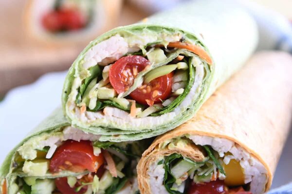 Turkey wrap in spinach tortilla stacked on two other wraps.