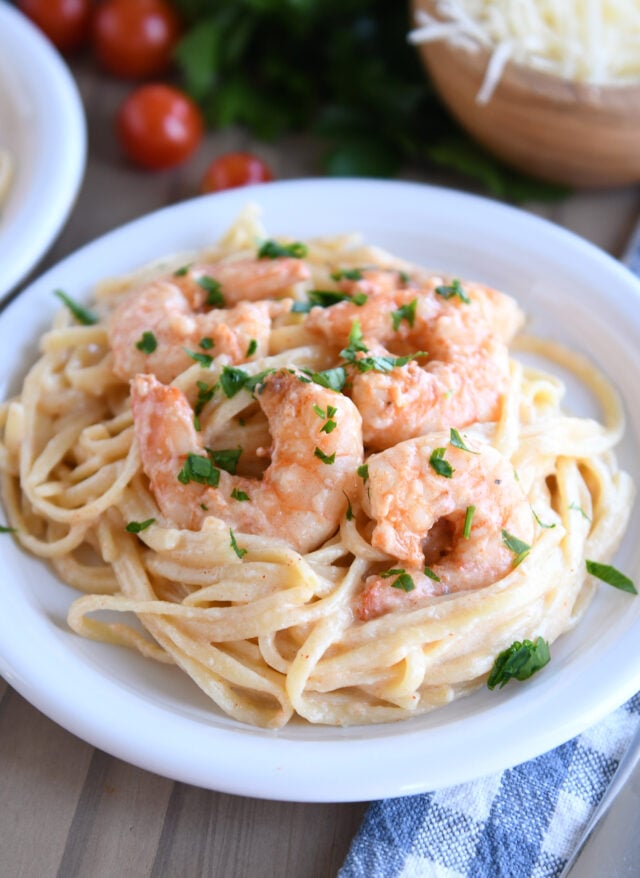 Shrimp with creamy pasta on white plate.