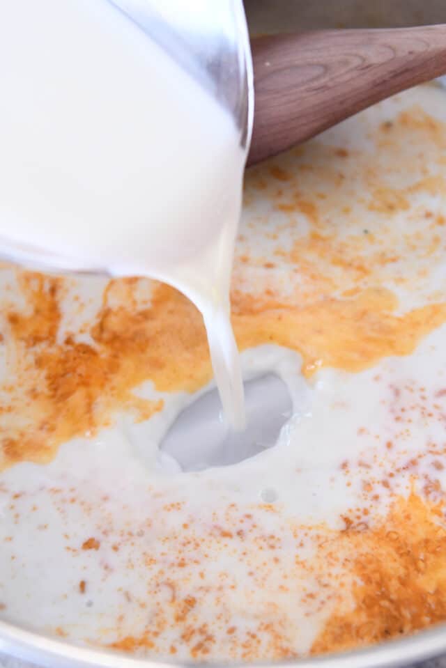 Pouring milk into skillet with paprika and butter.