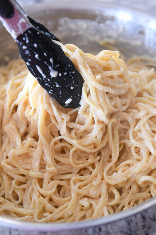 Toss the pasta into the cream sauce using tongs.