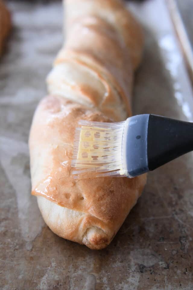 Bru،ng ،er on croissant french bread with pastry brush.